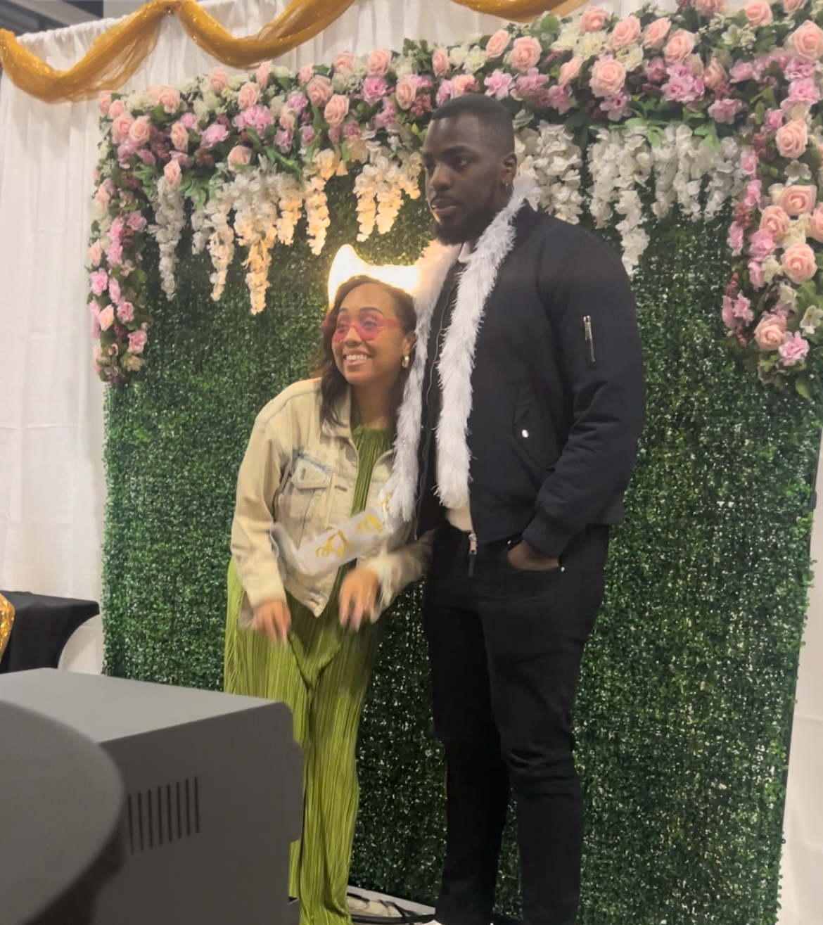Couple posing in front of the floral backdrop