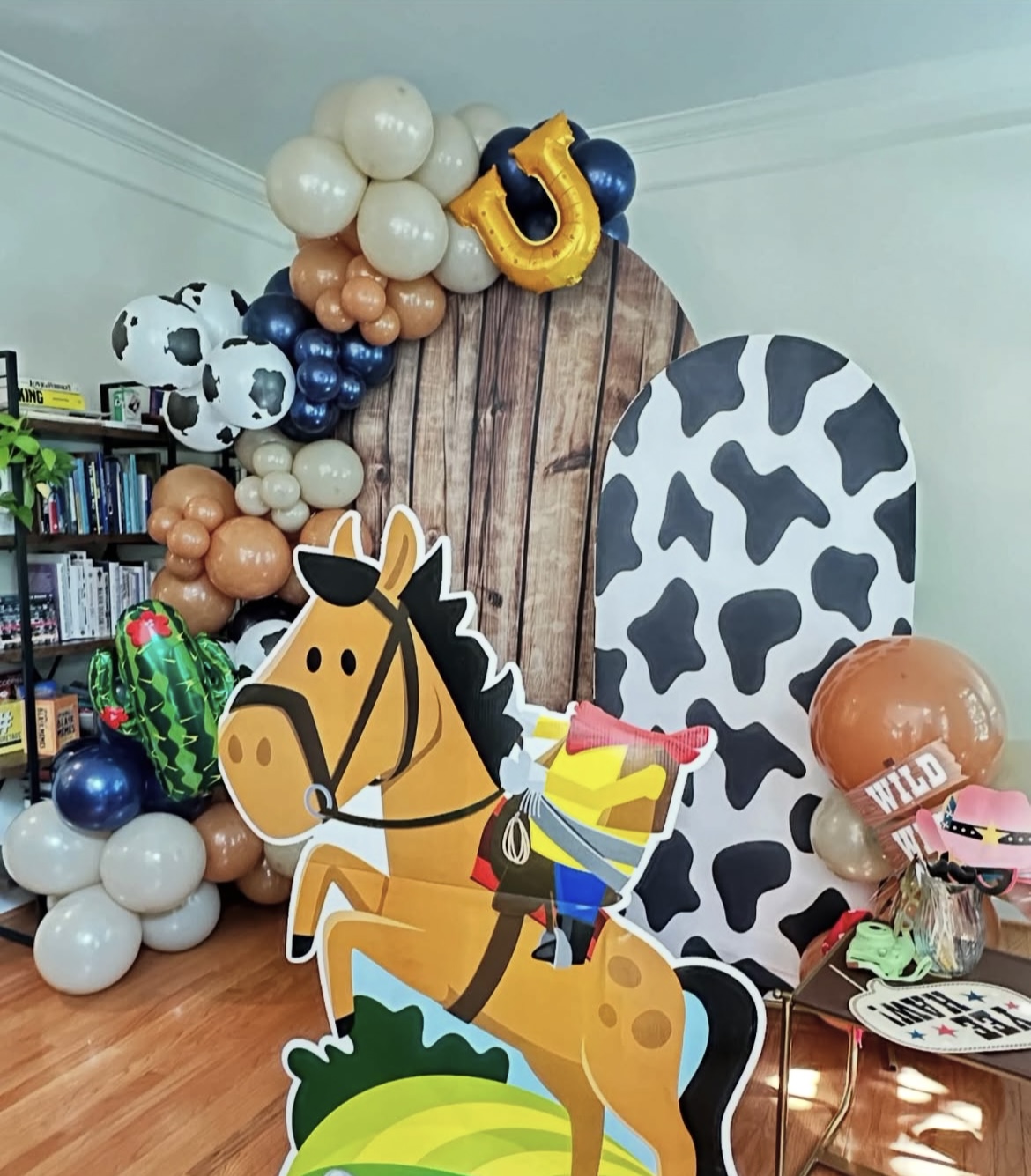 Cowboy themed balloon arch with horse cutout and cow print backdrop