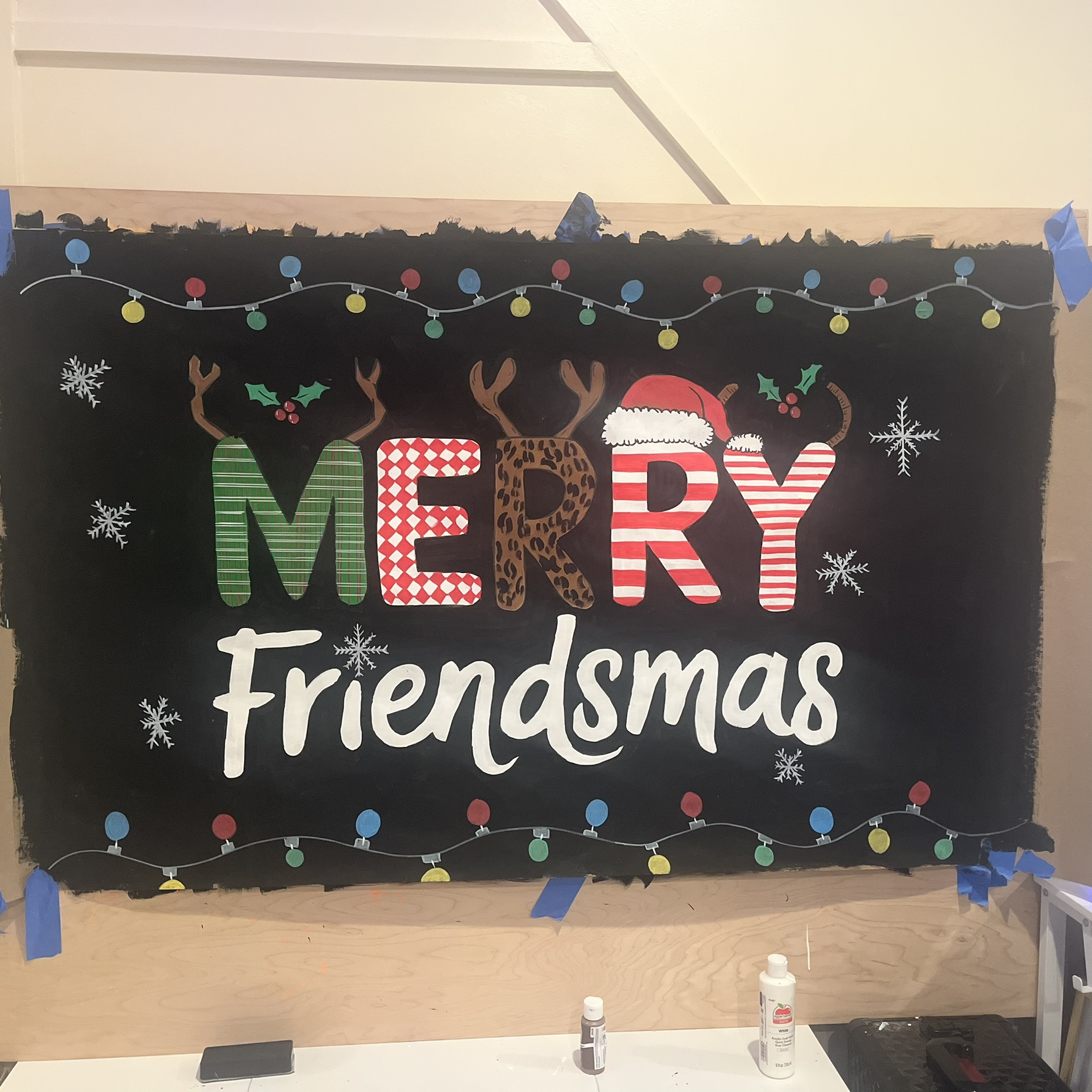 Hand painted Merry Friendsmas chalkboard sign with Christmas lights