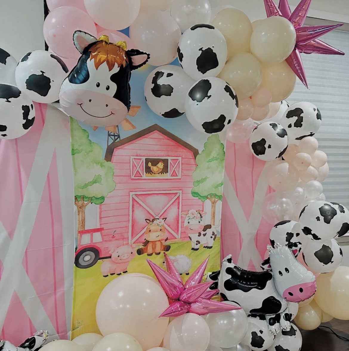 Pink barnyard farm themed backdrop with cow print balloon garland